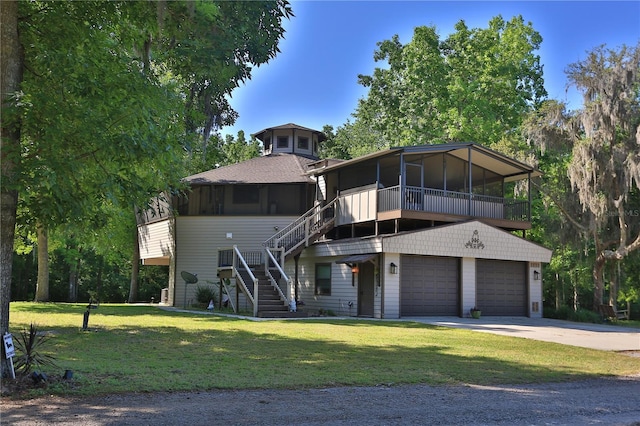 view of front of property featuring a sunroom, a garage, and a front lawn