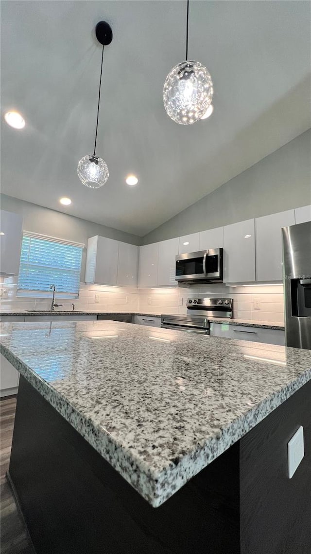 kitchen featuring white cabinetry, a kitchen island, appliances with stainless steel finishes, sink, and tasteful backsplash