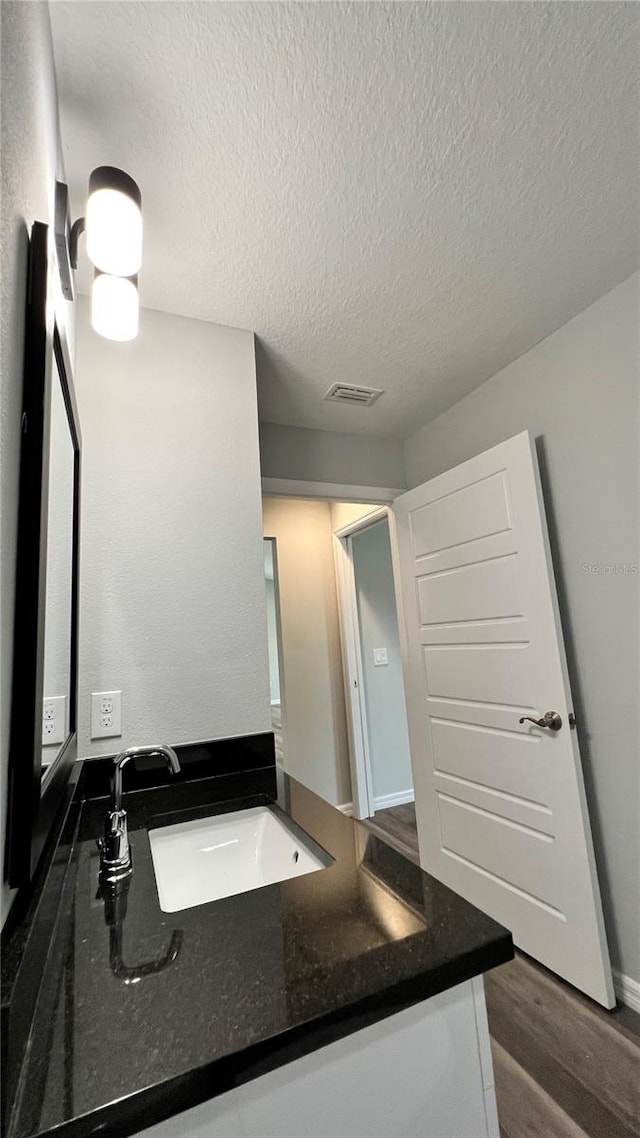 bathroom with hardwood / wood-style floors, vanity, and a textured ceiling