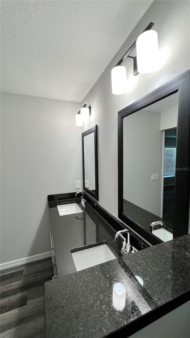 bathroom featuring dual sinks, vanity with extensive cabinet space, a textured ceiling, and hardwood / wood-style flooring