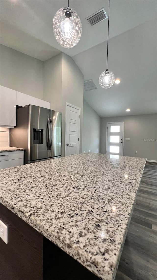 kitchen with dark hardwood / wood-style floors, light stone countertops, stainless steel refrigerator with ice dispenser, pendant lighting, and white cabinetry