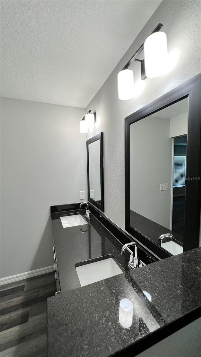 bathroom featuring oversized vanity, dual sinks, hardwood / wood-style flooring, and a textured ceiling