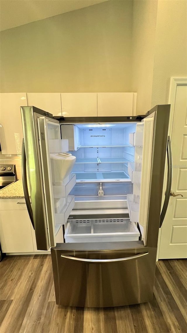 interior details with white cabinets, hardwood / wood-style floors, light stone countertops, and appliances with stainless steel finishes