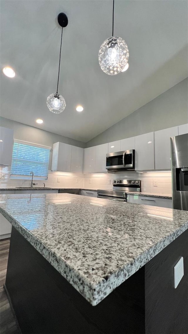 kitchen with a center island, appliances with stainless steel finishes, white cabinets, dark hardwood / wood-style floors, and tasteful backsplash