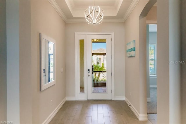 foyer with an inviting chandelier, light hardwood / wood-style floors, and a raised ceiling