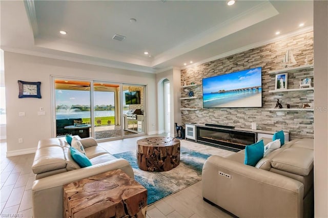 living room featuring a tray ceiling, a fireplace, light hardwood / wood-style floors, and crown molding