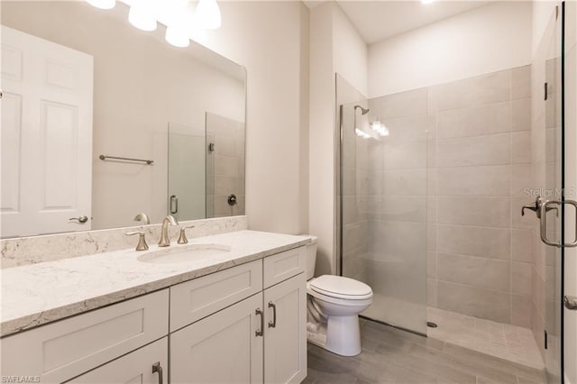 bathroom with a shower with door, toilet, and vanity