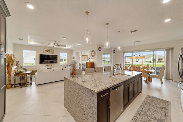 kitchen featuring light stone countertops, a kitchen island with sink, ceiling fan, sink, and dishwasher