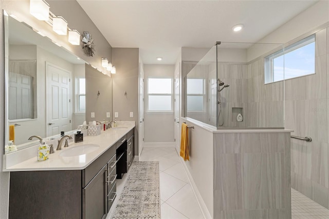 bathroom featuring tile patterned flooring, a tile shower, and vanity