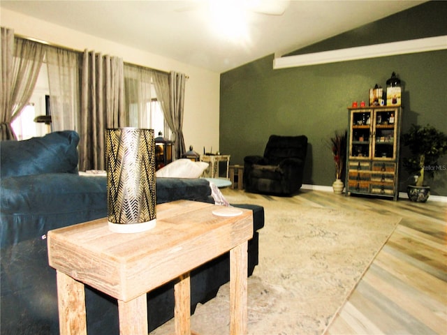 living area with vaulted ceiling, baseboards, and wood finished floors