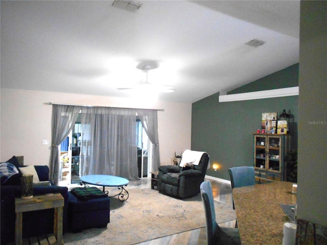 living area with a ceiling fan, lofted ceiling, visible vents, and wood finished floors