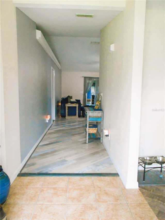 corridor featuring tile patterned flooring, visible vents, and baseboards