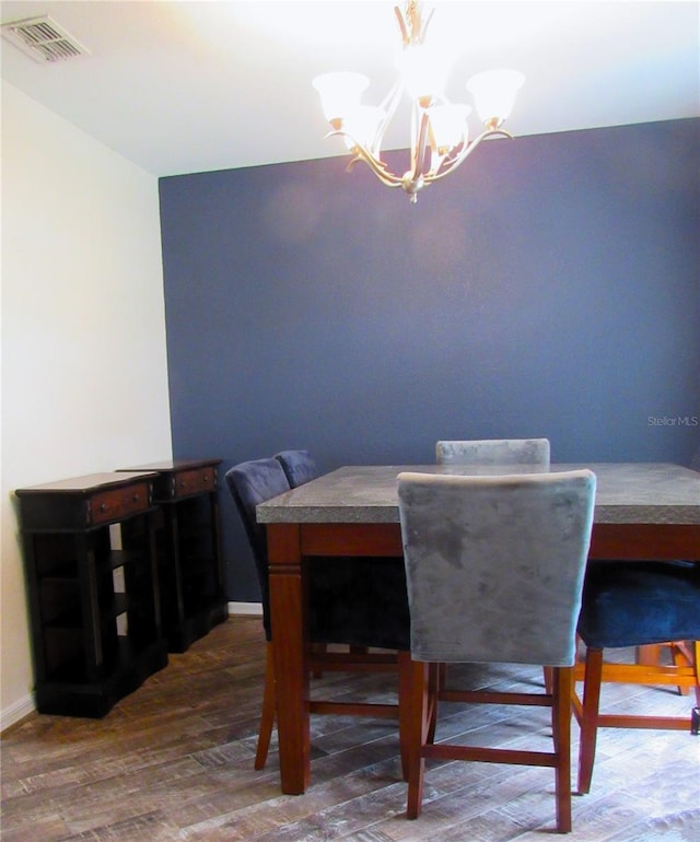 dining area with a chandelier, wood finished floors, visible vents, and baseboards