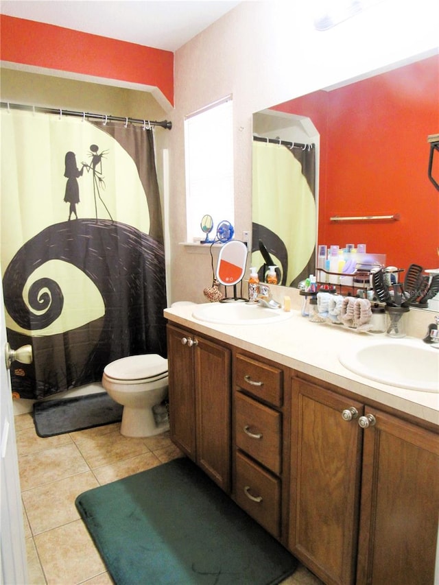 bathroom with double vanity, tile patterned flooring, a sink, and toilet