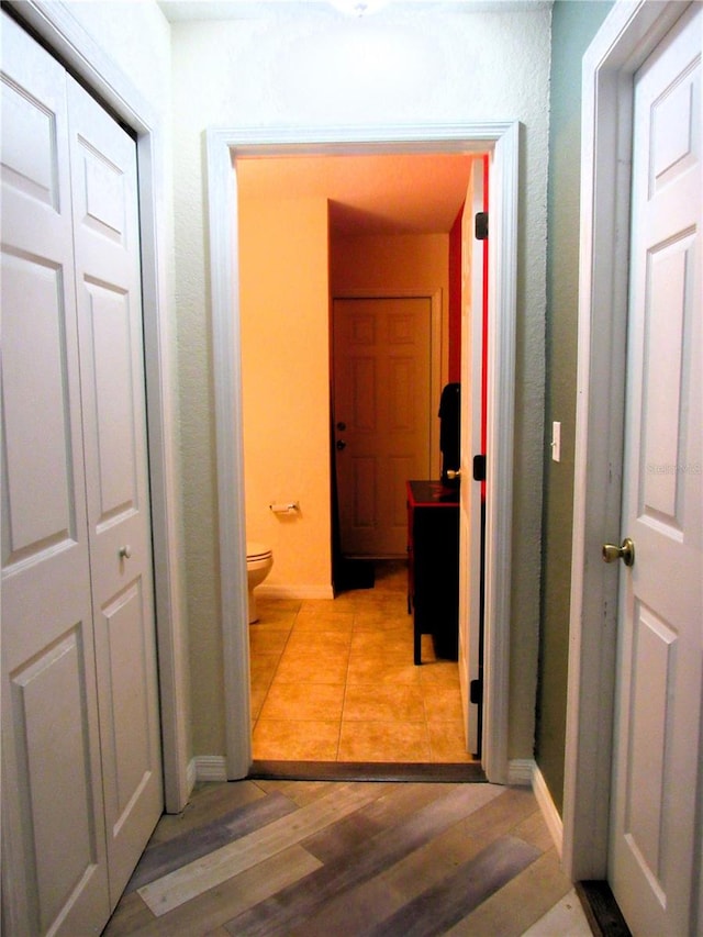 hall featuring light wood-type flooring and baseboards