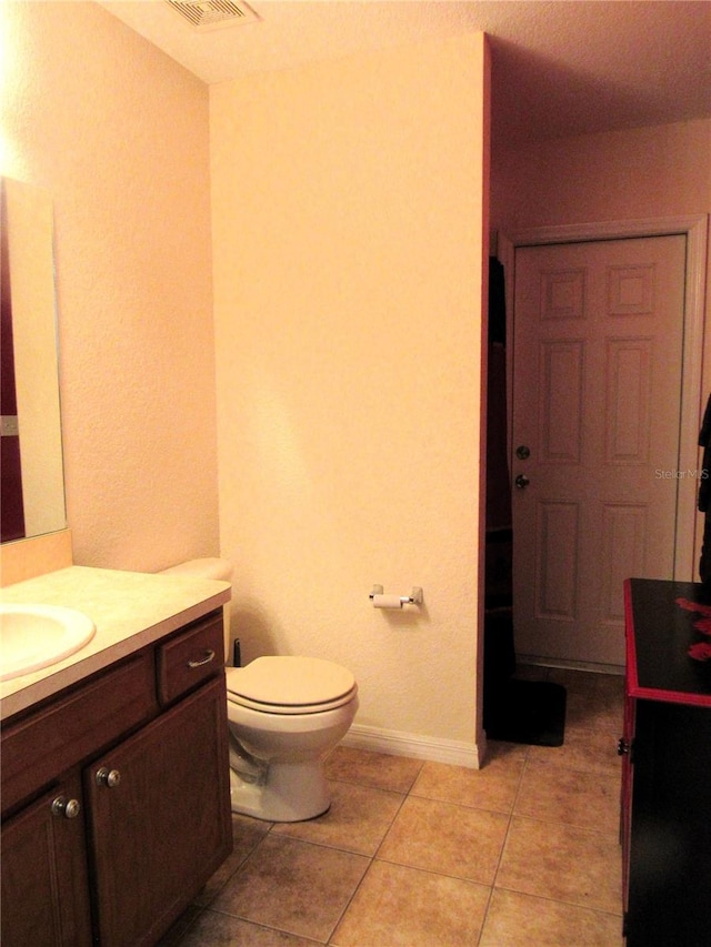 bathroom with baseboards, vanity, toilet, and tile patterned floors