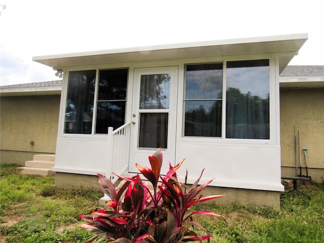 view of side of home with entry steps and stucco siding