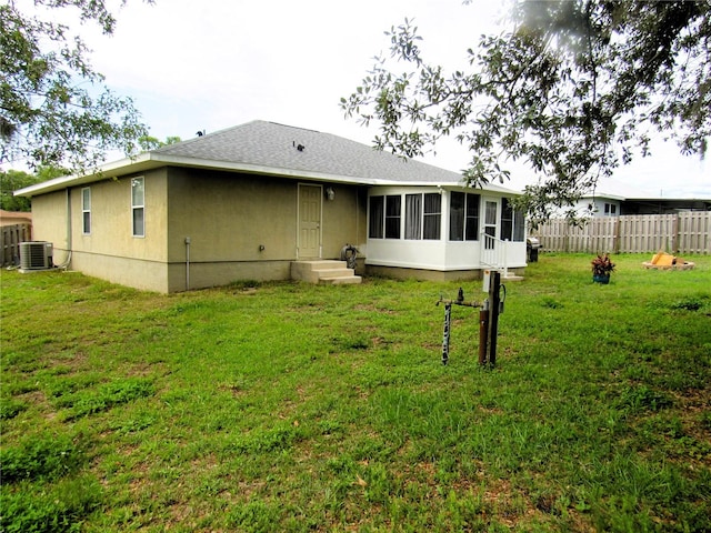 rear view of property featuring cooling unit, fence, a sunroom, a yard, and stucco siding