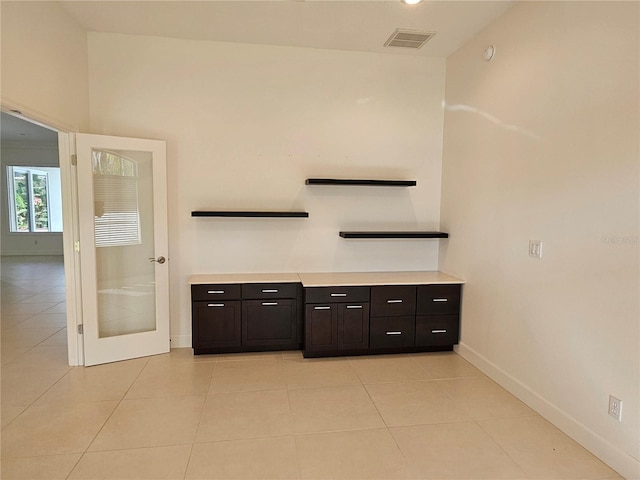 bar with dark brown cabinets and light tile floors