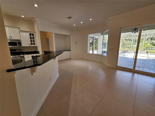 kitchen with light tile floors, white cabinets, kitchen peninsula, and range