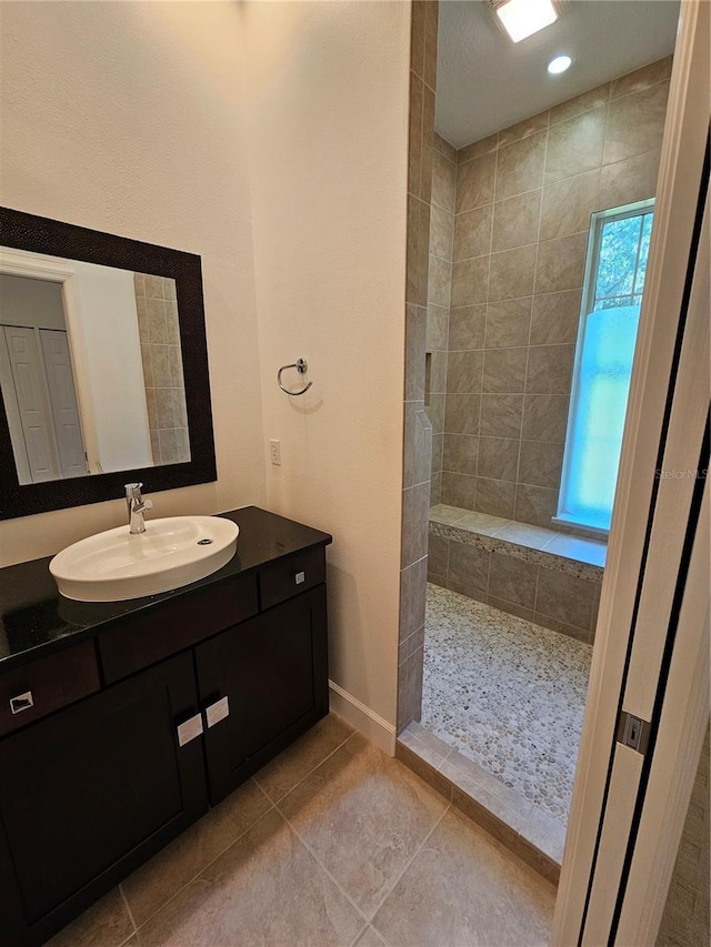 bathroom with tile floors, a tile shower, and vanity