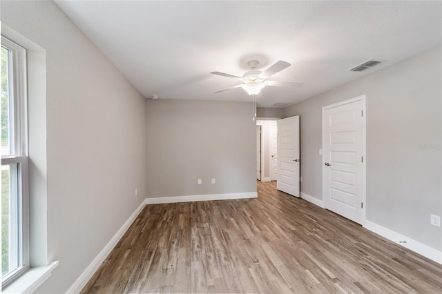 interior space with ceiling fan, wood finished floors, visible vents, and baseboards