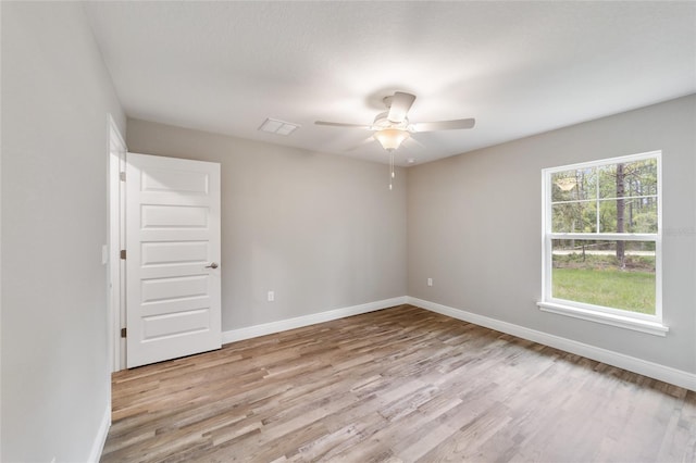 empty room featuring baseboards, ceiling fan, visible vents, and light wood-style floors