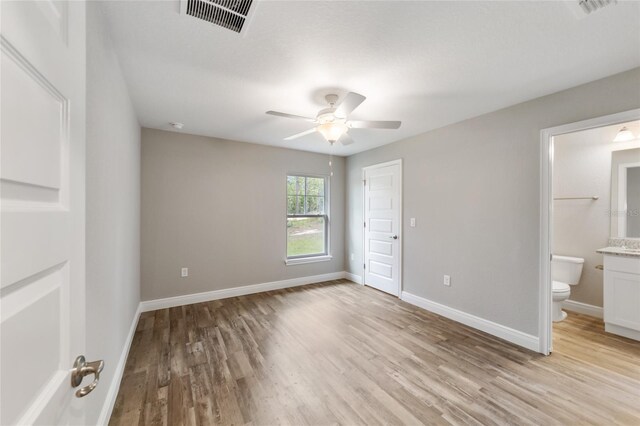 unfurnished bedroom with ensuite bathroom, light wood-type flooring, visible vents, and baseboards