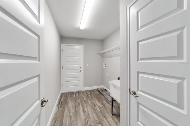 washroom with a textured ceiling, hookup for a washing machine, laundry area, wood finished floors, and baseboards