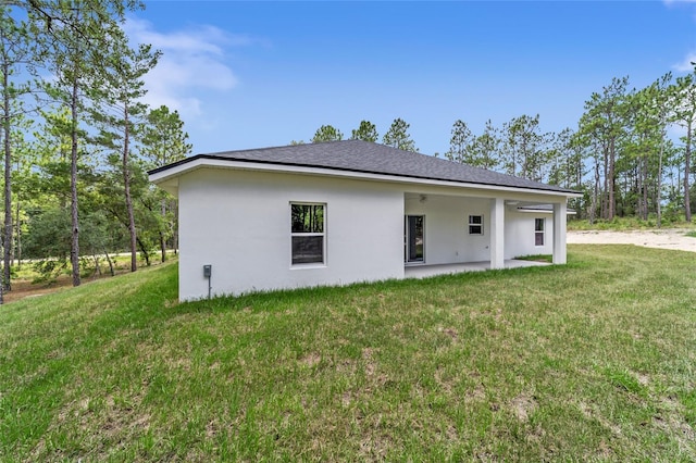 rear view of property with ceiling fan, a yard, a patio area, and stucco siding