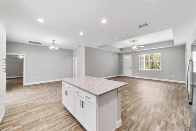 kitchen featuring visible vents, open floor plan, a tray ceiling, and ceiling fan with notable chandelier