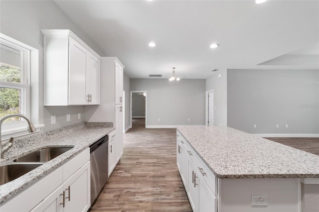 kitchen featuring visible vents, white cabinets, a center island, stainless steel dishwasher, and a sink