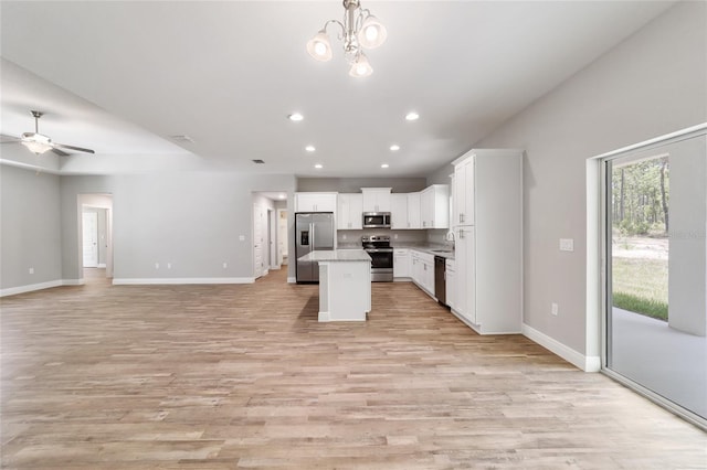 kitchen featuring a kitchen island, white cabinets, open floor plan, light countertops, and appliances with stainless steel finishes