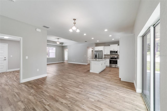 kitchen featuring a center island, visible vents, appliances with stainless steel finishes, open floor plan, and white cabinetry