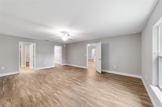 empty room featuring light wood finished floors, ceiling fan, and baseboards