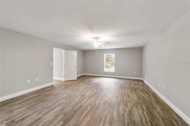 spare room with a textured ceiling, ceiling fan, wood finished floors, and baseboards