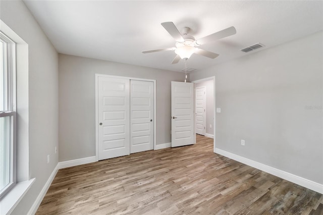 unfurnished bedroom featuring a closet, visible vents, ceiling fan, wood finished floors, and baseboards