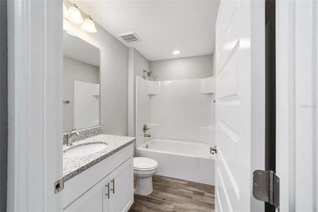 bathroom with visible vents, shower / bathing tub combination, toilet, vanity, and wood finished floors