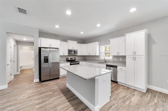 13359 SW 80th St, Dunnellon, FL 34432 - kitchen with stainless steel appliances, a sink, white cabinets, light wood-type flooring, and a center island