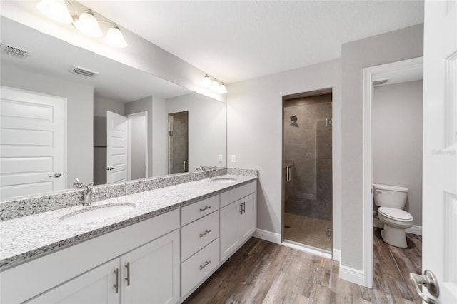 13359 SW 80th St, Dunnellon, FL 34432 - bathroom featuring a stall shower, wood finished floors, double vanity, baseboards, and toilet