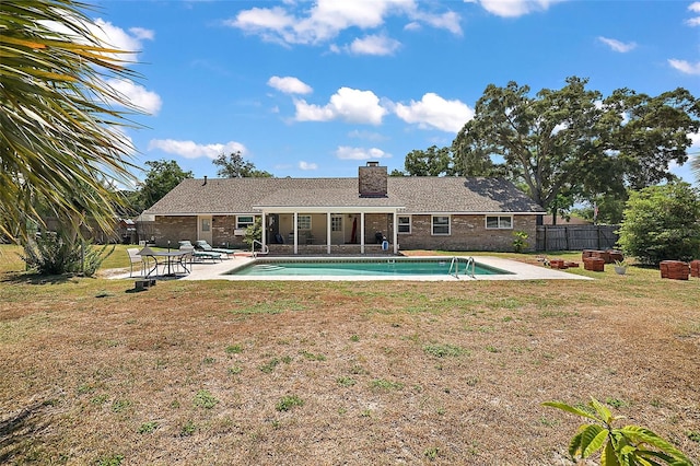 back of property with a fenced in pool, a patio area, and a lawn