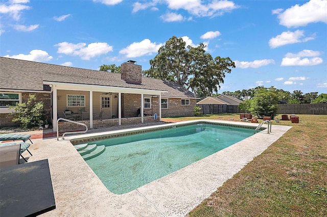 view of swimming pool with ceiling fan, a yard, and a patio