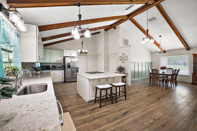 kitchen featuring stainless steel fridge, sink, high vaulted ceiling, white cabinets, and a kitchen island