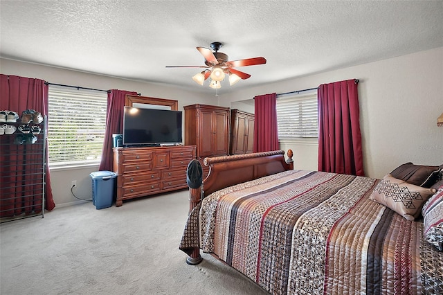 carpeted bedroom with ceiling fan and a textured ceiling