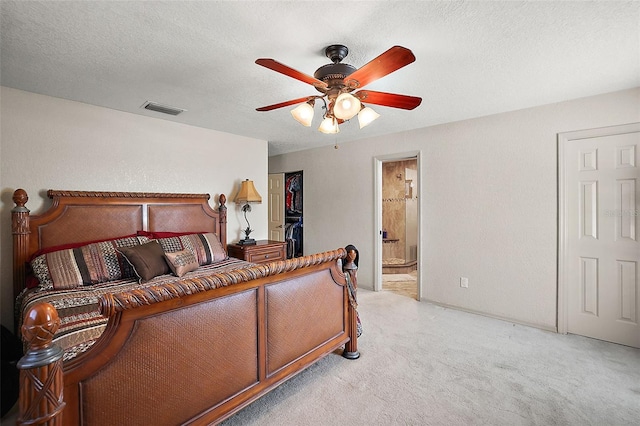 bedroom featuring ensuite bath, ceiling fan, light carpet, and a textured ceiling