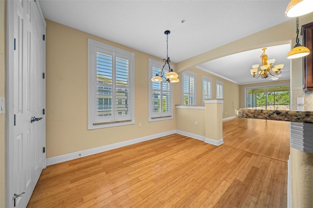 unfurnished dining area with a healthy amount of sunlight, light hardwood / wood-style flooring, and a chandelier