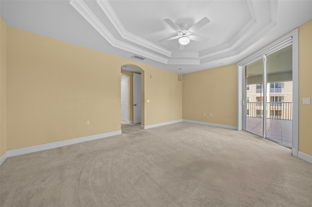 unfurnished room with a tray ceiling, crown molding, ceiling fan, and light colored carpet