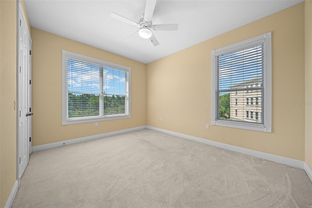 spare room with light carpet, a wealth of natural light, and ceiling fan