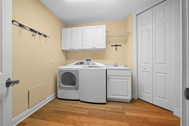 laundry room with sink, light hardwood / wood-style floors, washing machine and clothes dryer, and cabinets