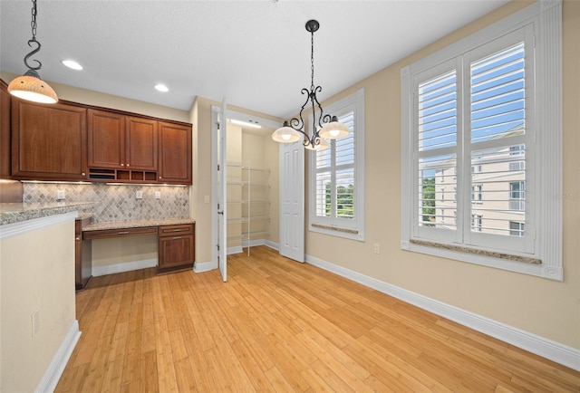 kitchen featuring hanging light fixtures, light hardwood / wood-style floors, tasteful backsplash, and a chandelier